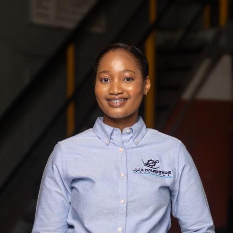 Professional portrait of JJ, founder and lead engineer at JJ and Daughters Solutions, wearing business attire in modern office setting